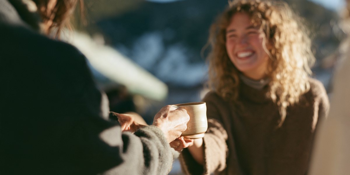 Made in Tahoe Spring Festival Artisan handing a handmade ceramic mug to a smiling customer at an outdoor market