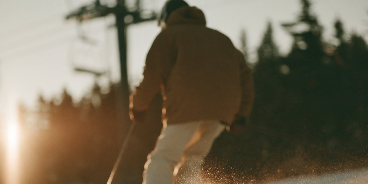 Northstar California Opening Day Skier carving fresh corduroy past a chairlift at sunrise, snow spraying off the edges