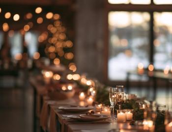 Candlelit holiday dinner table with glassware and evergreen garnish in a mountain lodge