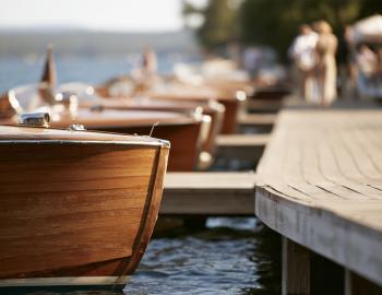 Polished wooden classic boats lined up along a lakeside dock