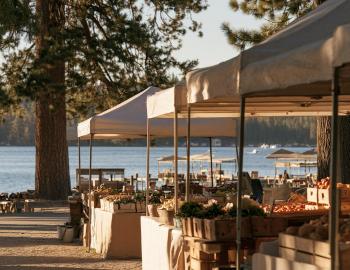 Tahoe City Farmers' Market Farmers market tents with fresh produce under pines beside Lake Tahoe