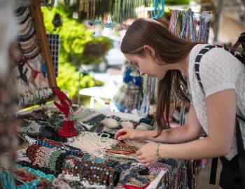 A woman looks at jewelry at a craft booth