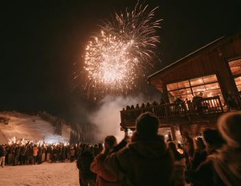 Fireworks over a ski lodge as a torchlight parade descends the slope on New Year's Eve