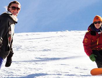 two people snowboarding down a mountain