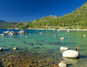 Shallow waters of tahoe, calm shallow waters with boulders and people standing and kayaking 