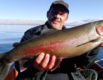 man holding large mackinaw fish from tahoe