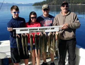 four people holding a stick with the fish they caught 