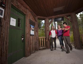 three people walking into the front door of a cabin