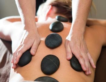 woman laying face down with rocks along her spine