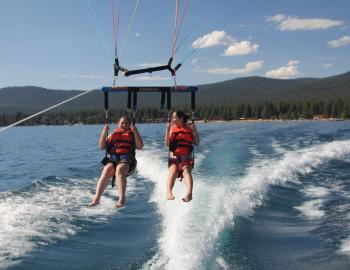 two girls parasailing behind boat feet almost touching the water