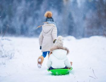 child pulling a child on a snow sled