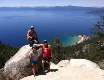 three people on boulders high above the tahoe waters