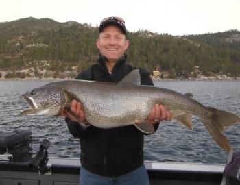man holding a large fish he caught in tahoe