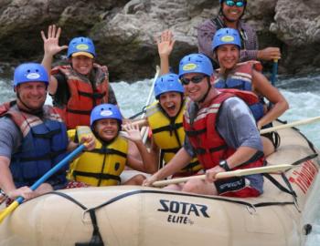 people in large white water raft in river