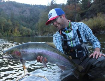 man showing fish that he just caught in river