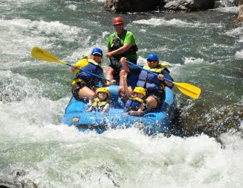 people in a large white water raft going down the river