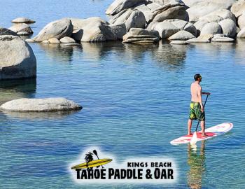 man on stand up paddle board on calm waters with boulders in water around