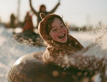 Tube-or-Treat at Sugar Bowl Laughing child in a costume spinning down a snow tubing lane as snow sprays