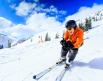 A person smiles gleefully while they ski down a groomed mountain on a clear day