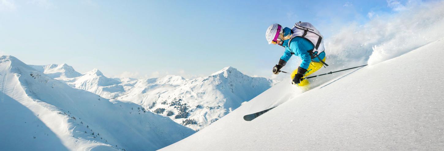 man skiing down hill in fresh powder