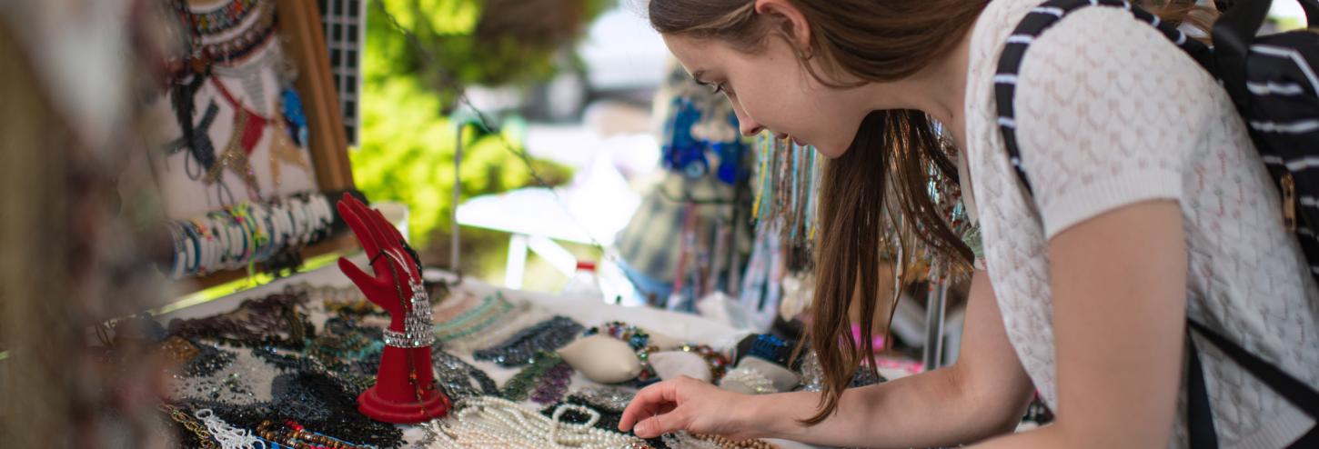 A woman looks at jewelry at a craft booth