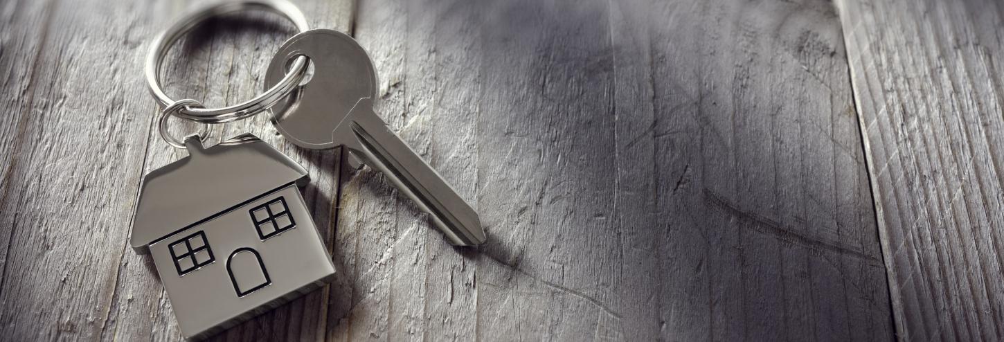 A key with a home keychain sits on a table