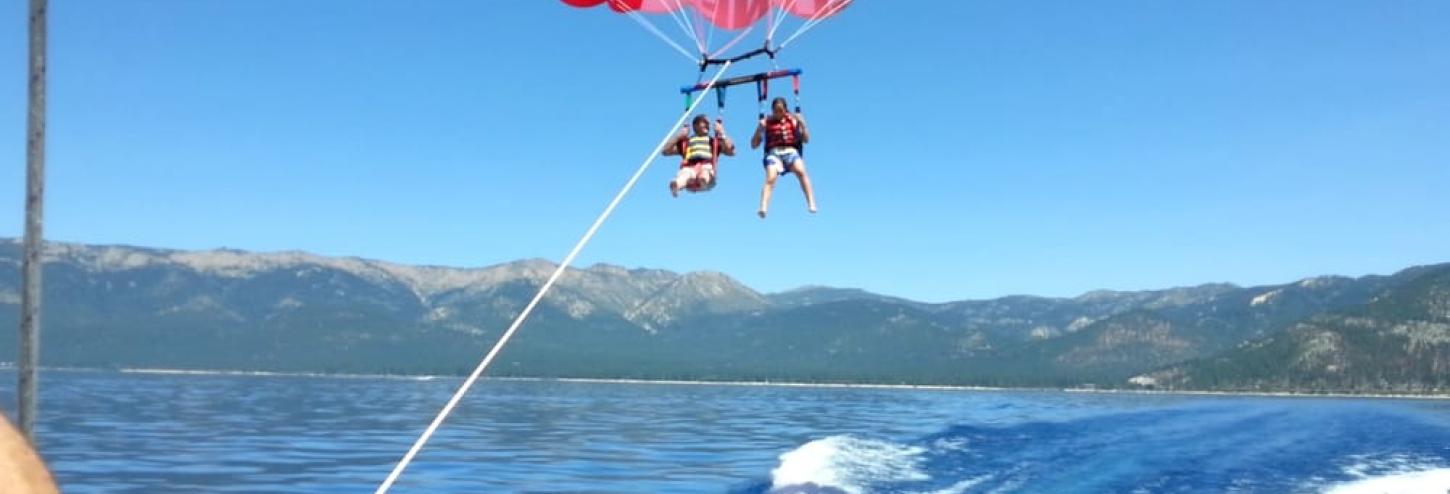 two people parasailing in the air behind boat