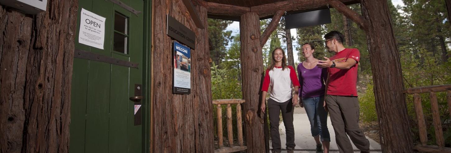 three people walking into the front door of a cabin