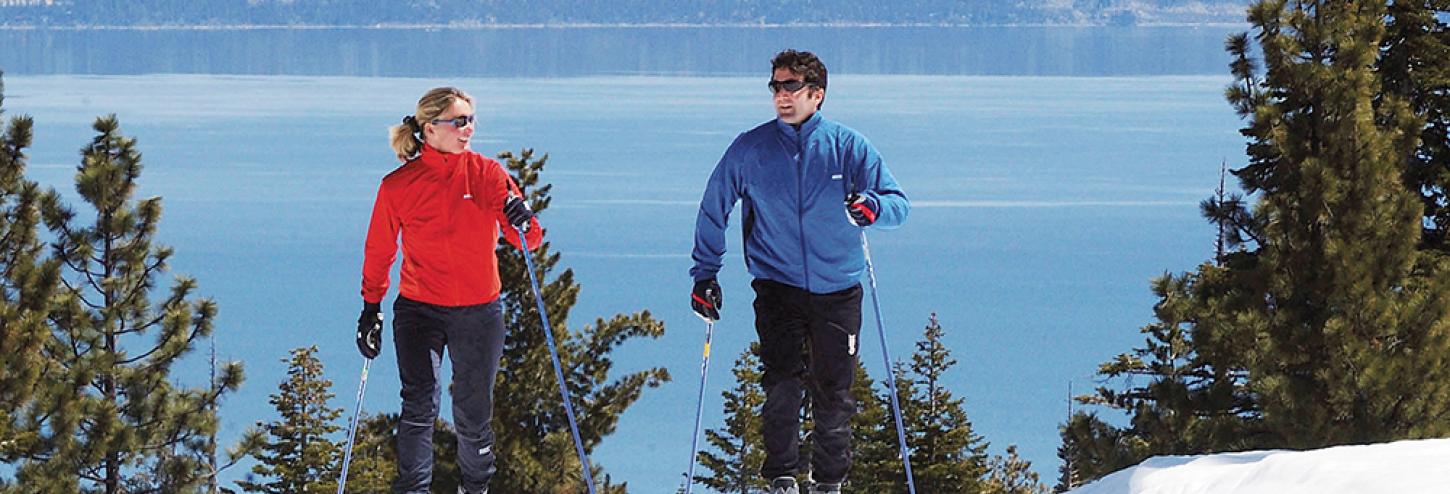 two people cross country skiing with lake in the background