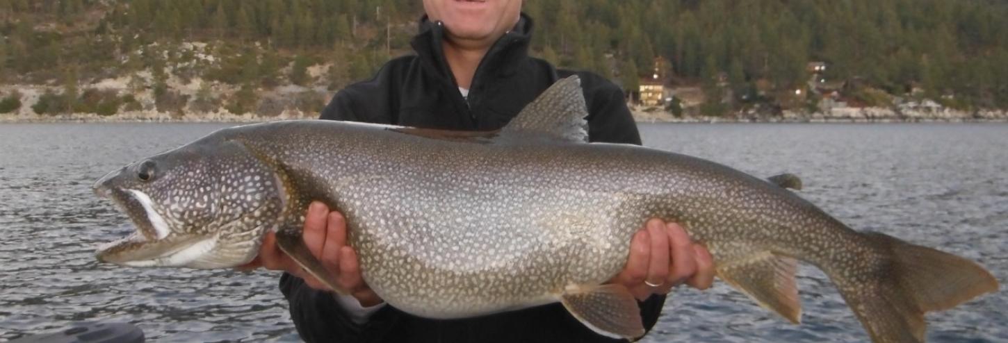 man holding a large fish he caught in tahoe