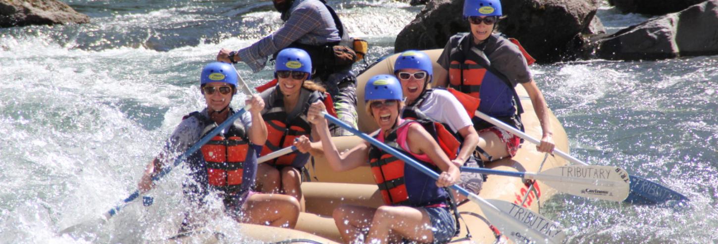 people in large white water raft in river