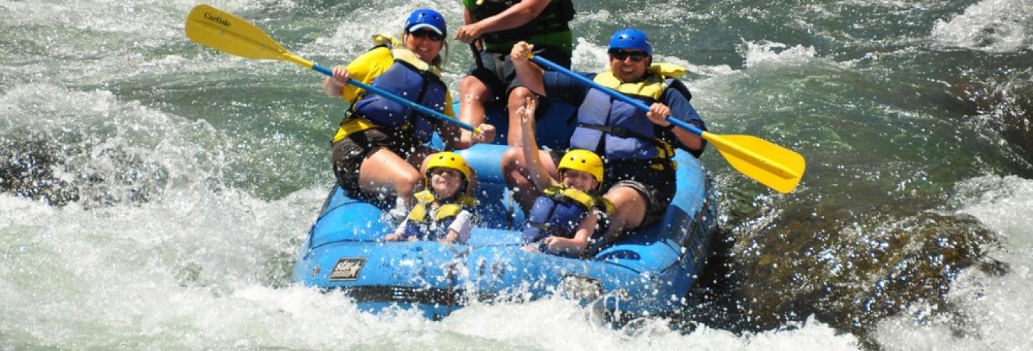 people in a large white water raft going down the river