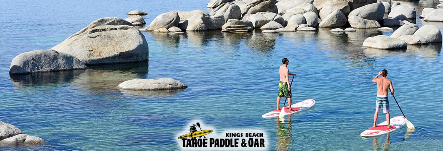 man on stand up paddle board on calm waters with boulders in water