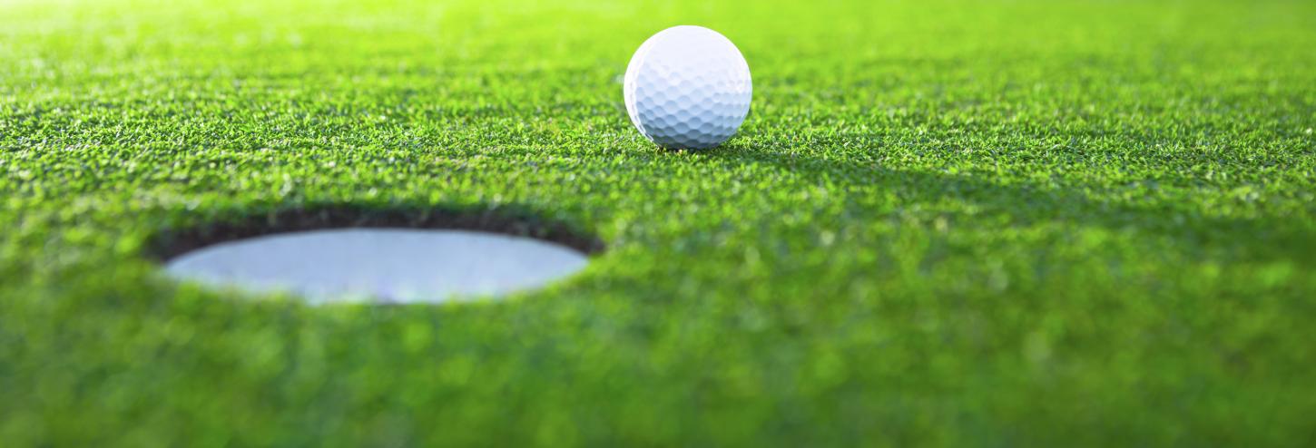 golf ball near the hole on the green
