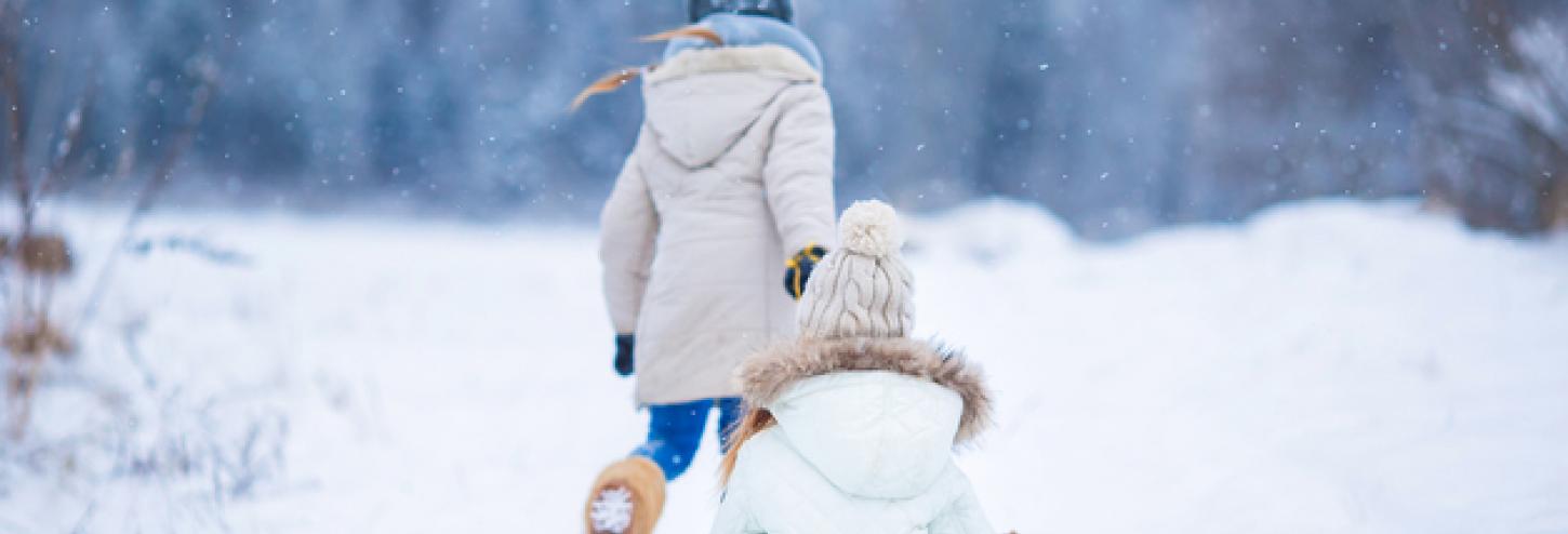 child pulling a child on a snow sled