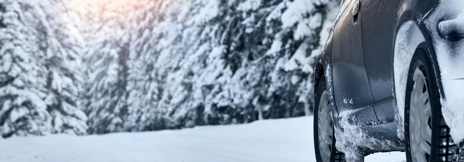 snowy road with car driving on it