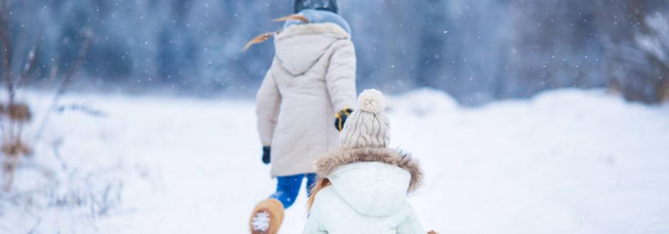 kid walking in the snow pulling a sled