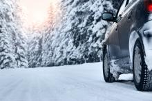 snowy road with car driving on it