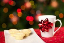 white cup with red ribbon next to a plate of snacks for sants