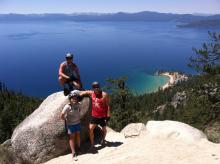 Three mountain bikers posing on rocks with lake in background