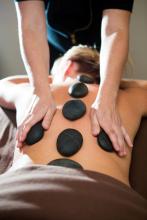 woman laying face down with rocks along her spine