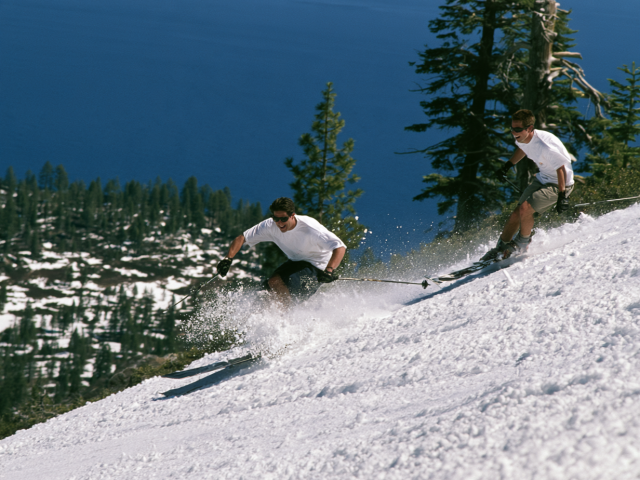 Two friends skiing down a Tahoe mountain in springtime