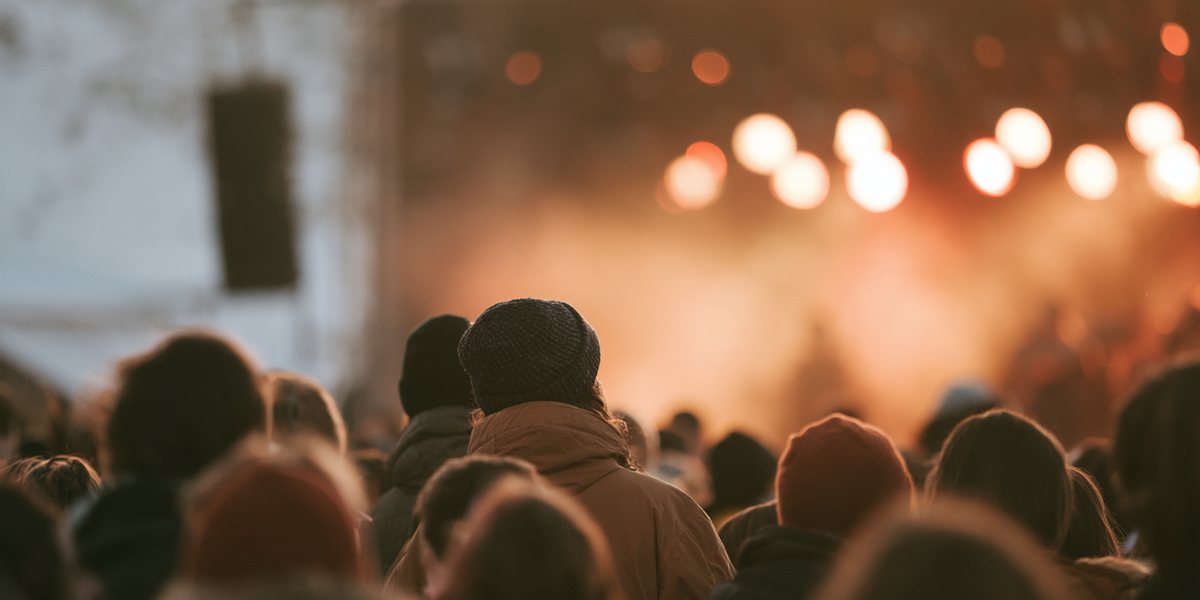 Tahoe Live at Palisades Tahoe Winter concert crowd in beanies facing a warmly lit outdoor stage
