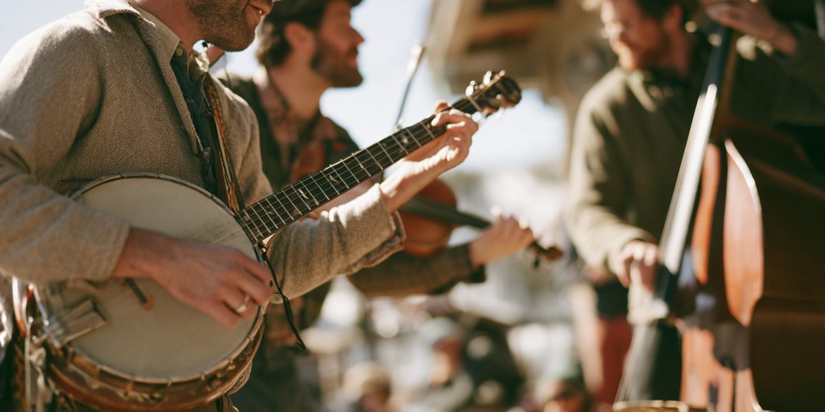A Little Dose of WonderGrass at Palisades Tahoe Banjo, fiddle and upright bass players performing at a sunny outdoor bluegrass festival